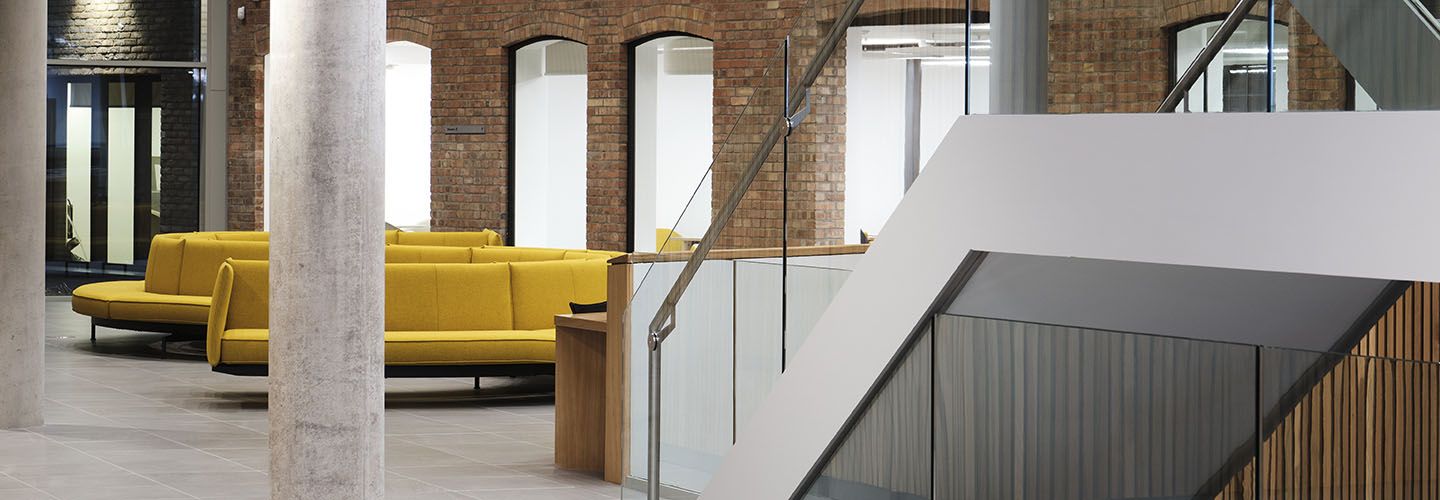Internal of the Law School Building at ground floor level looking at stairs, yellow sofas and archways