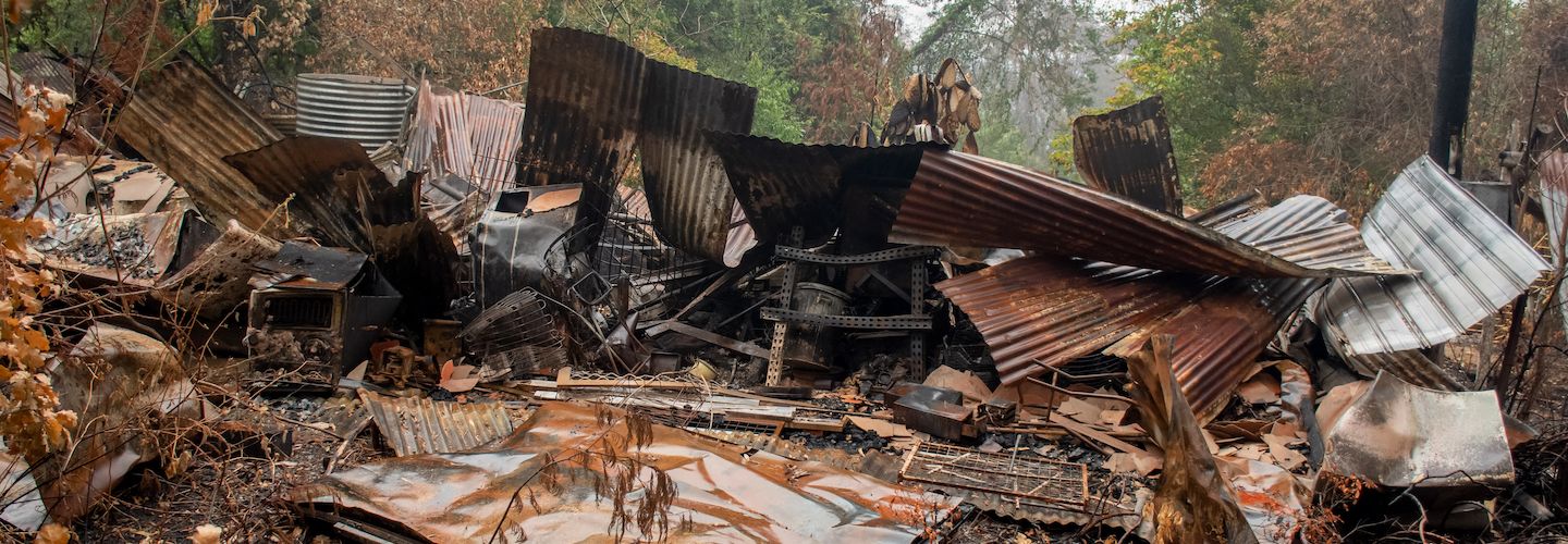 A collection of burnt buildings and rubble, surrounded by trees