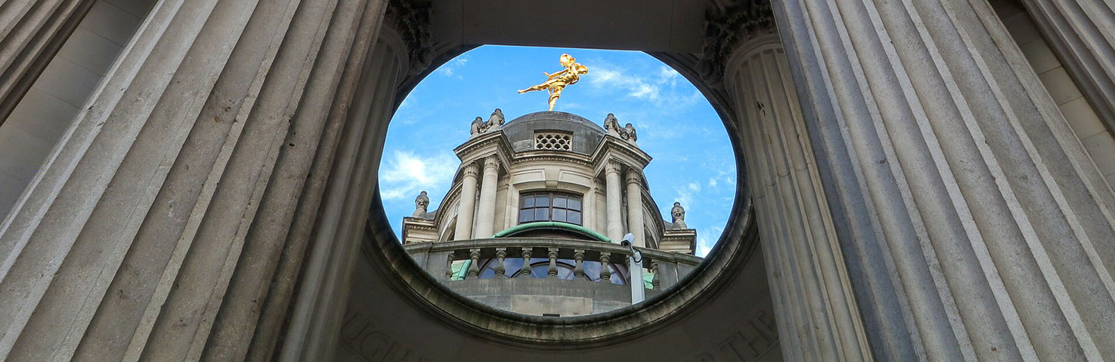 A brass sculpture on top of part of the Bank of England