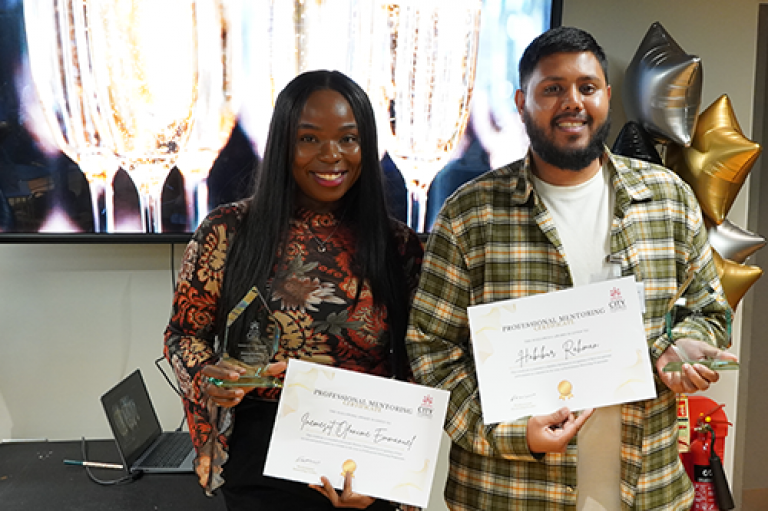 A man and woman hold a certificate and smile at an awards ceremony