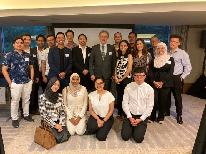 Alumni and Dr Russell Gerrard group together with around 15 men and women standing and sitting in a group