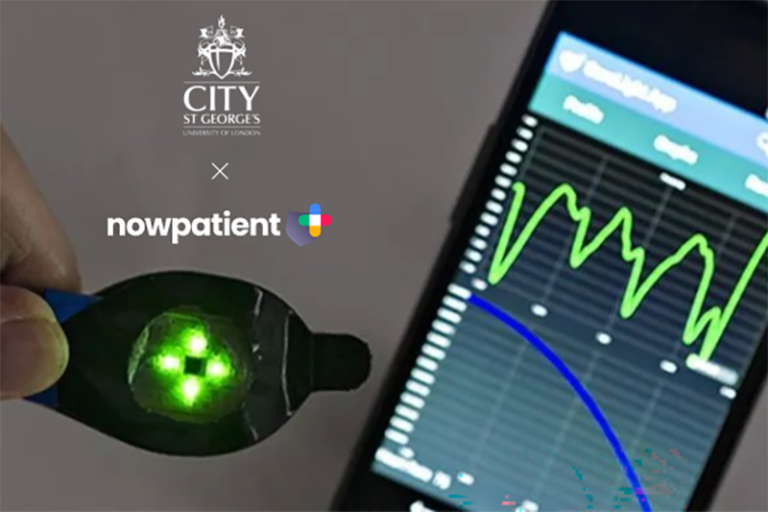 Hand holding a green-lit medical device next to a smartphone showing health data