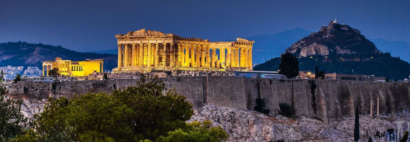 Parthenon lit up against a bright blue sky at dusk