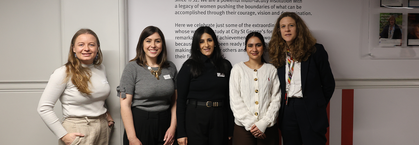A group of women dressed in smart attire pose for a photo 