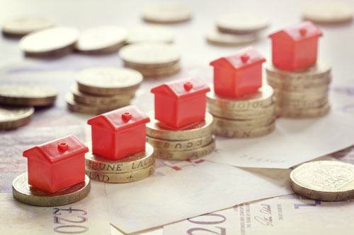 	Minature houses resting on pound coin stacks