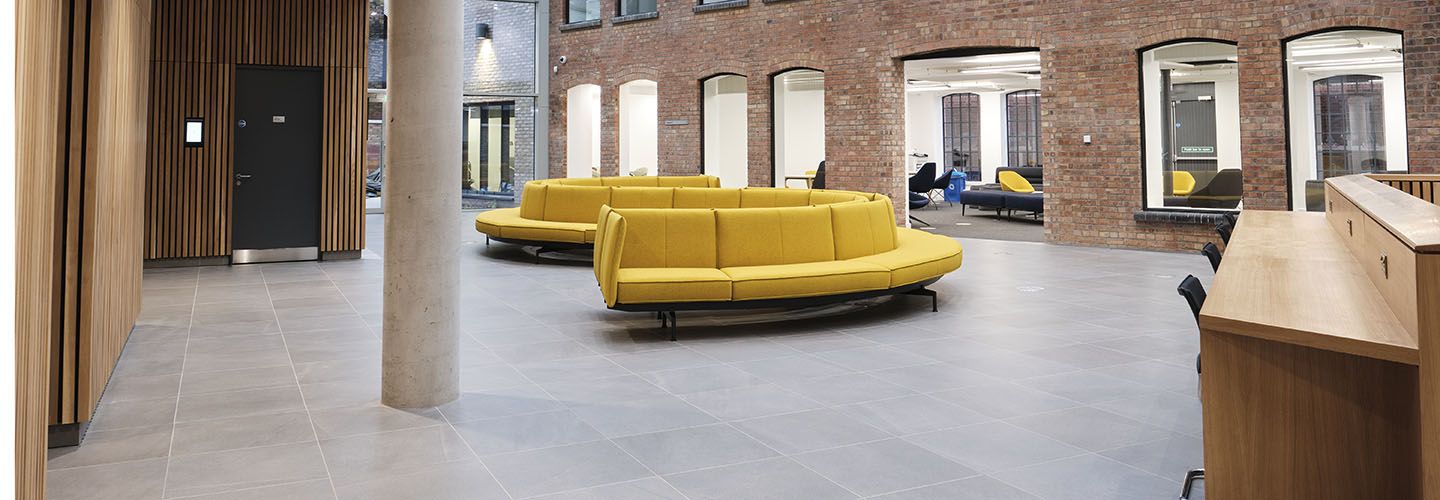 Internal of Law School Building at ground floor level looking at yellow sofas and archways leading to rooms.