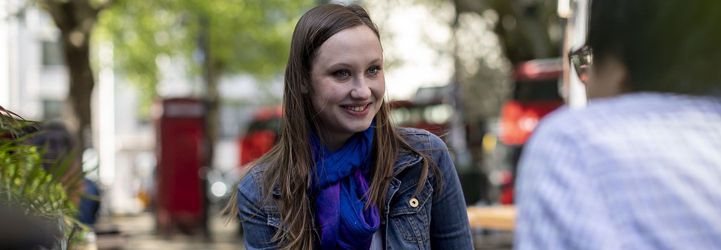 Female student in conversation at a picnic table in a park.