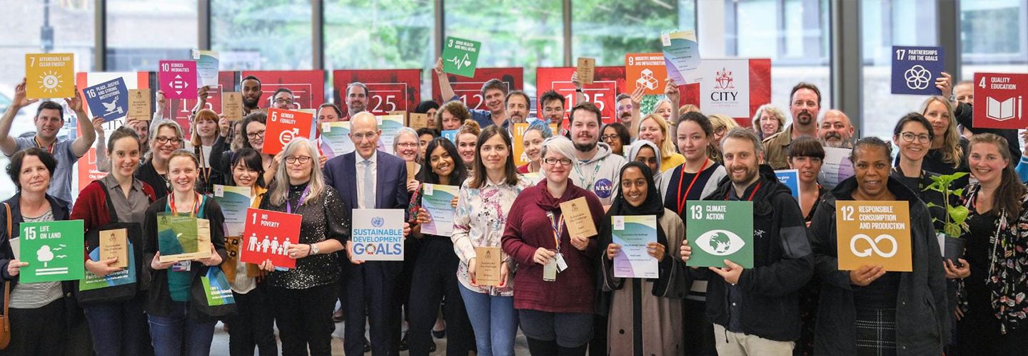 Staff and students smiling holding signs about sustainability goals