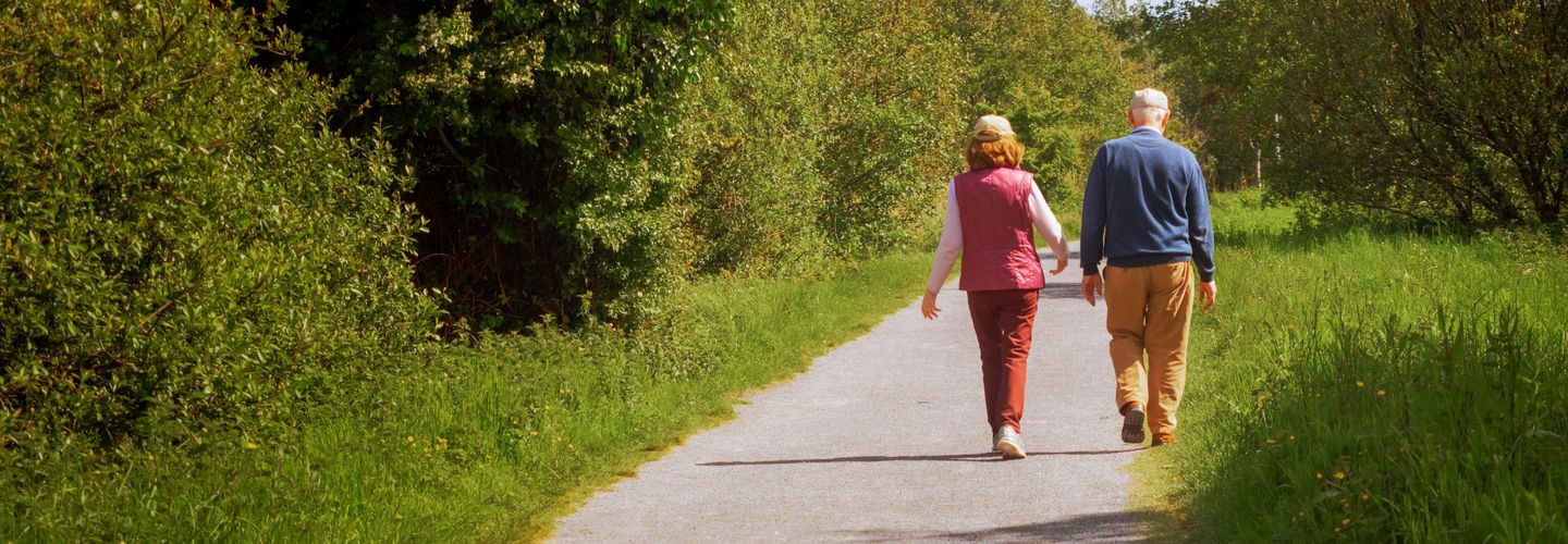 Old couple walking on a footpath on a warm sunny day.