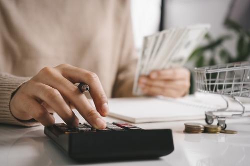 A hand calculates sums and counts cash