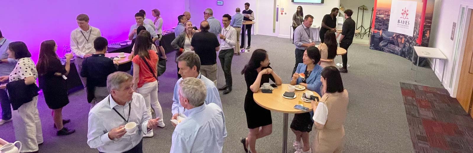 Wide angle image of a group of mergers and acquisitions experts at a conference at Bayes Business School