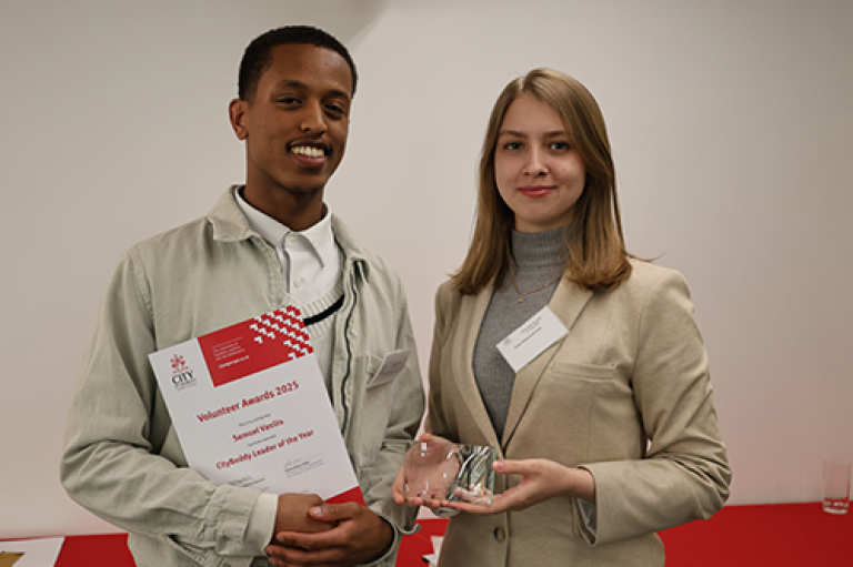 A man and woman hold a certificate and an award and pose for a photo