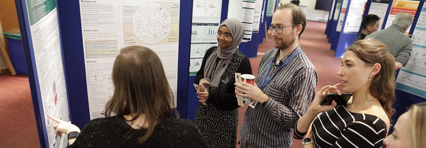 Researchers stood around poster in board room