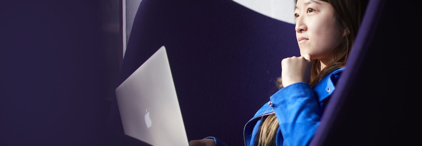 Female student sitting on a purple couch in the library