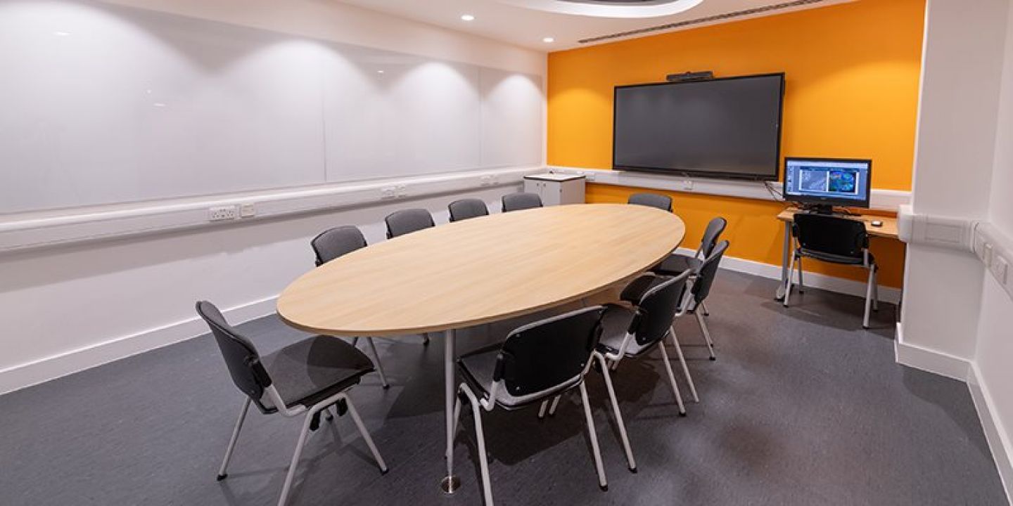 Empty base room with chairs round table in front of digital screen mounted on wall