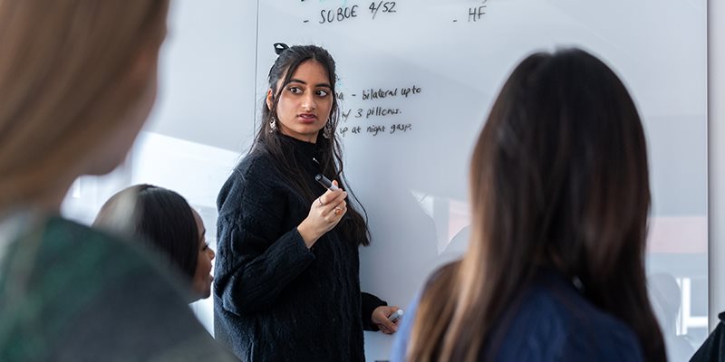 Students stood Infront of white board in front of other students