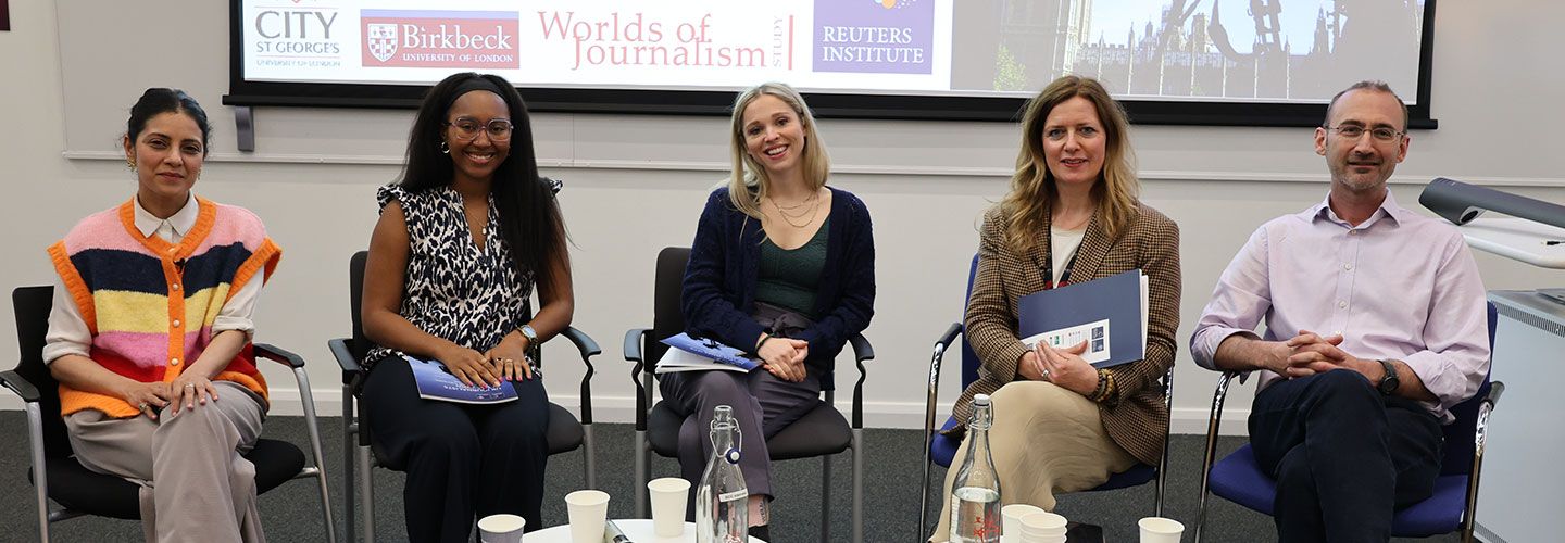 An image of the speakers sitting down and smiling to camera. Behind them is a big screen showing the logos of the various partner organisations of the research study