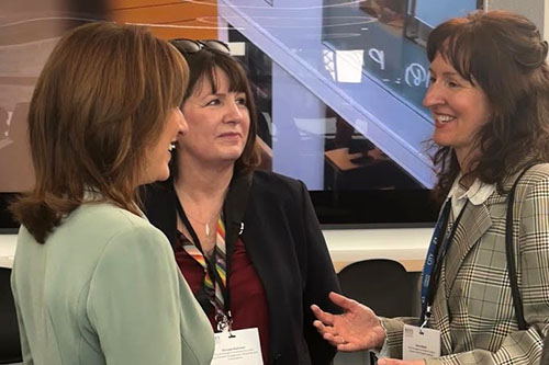 Three women standing together in conversation.