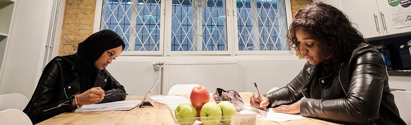 Two students working at a table in the English common room.