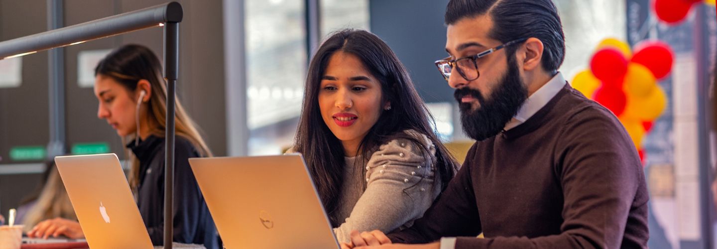 Male and female students working together whilst using laptops