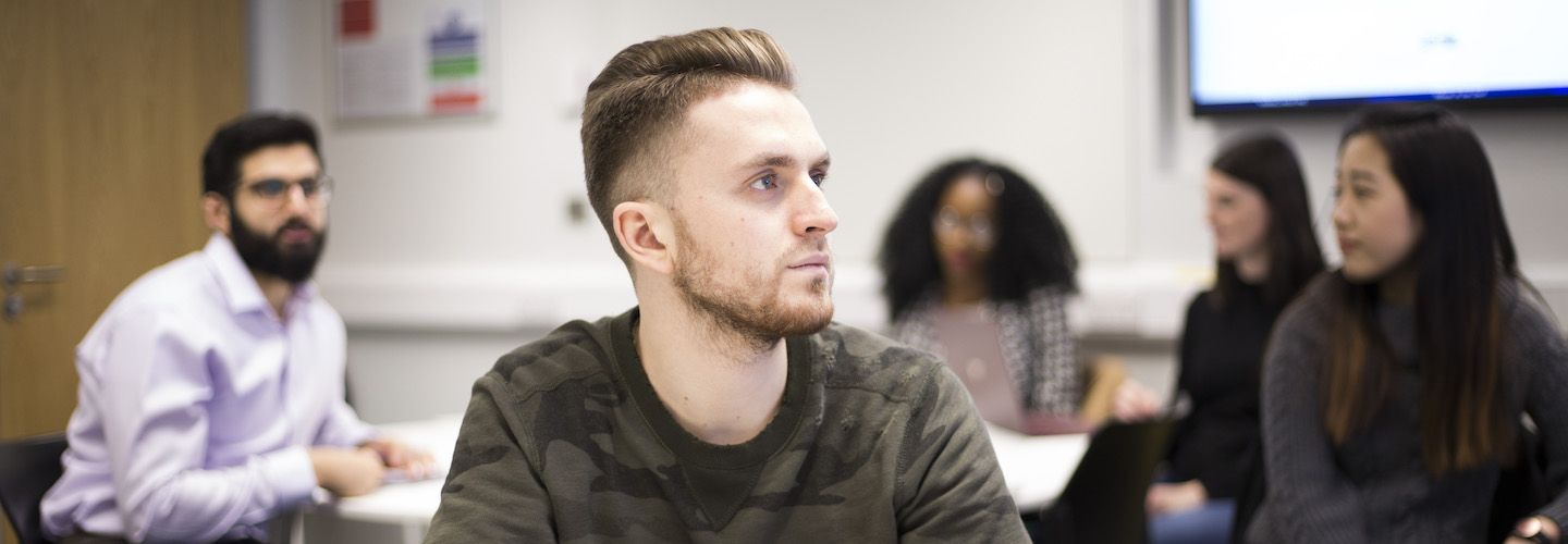 A male student looking forwards and listening in a lecture