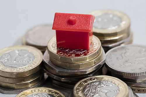 A house sits atop a pile of coins