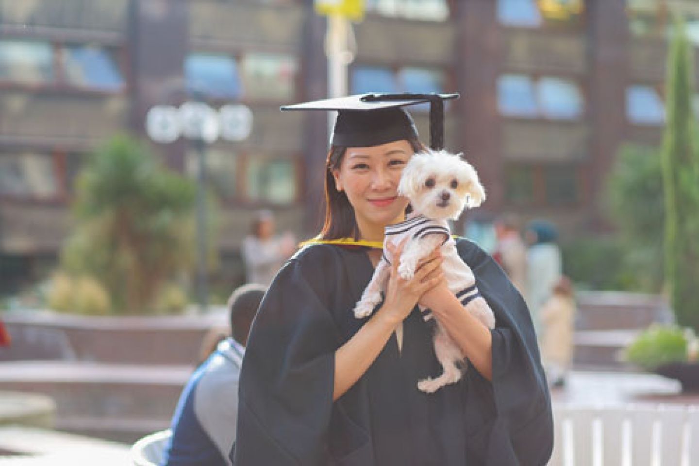 Female graduate shares her proud moment with her pet dog.