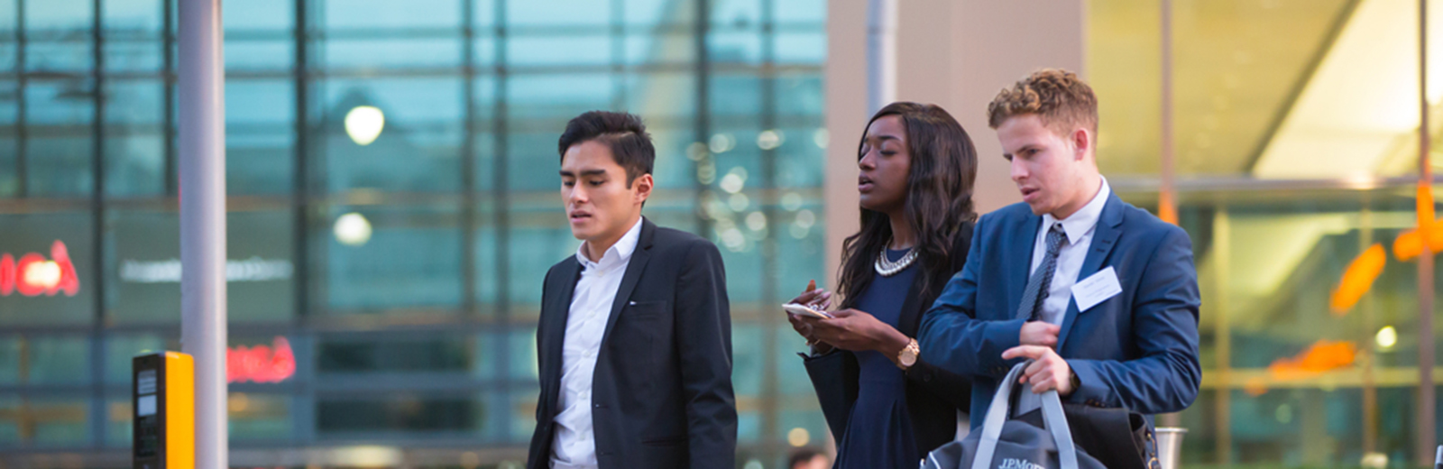 Two men and a woman in suits walking along the road