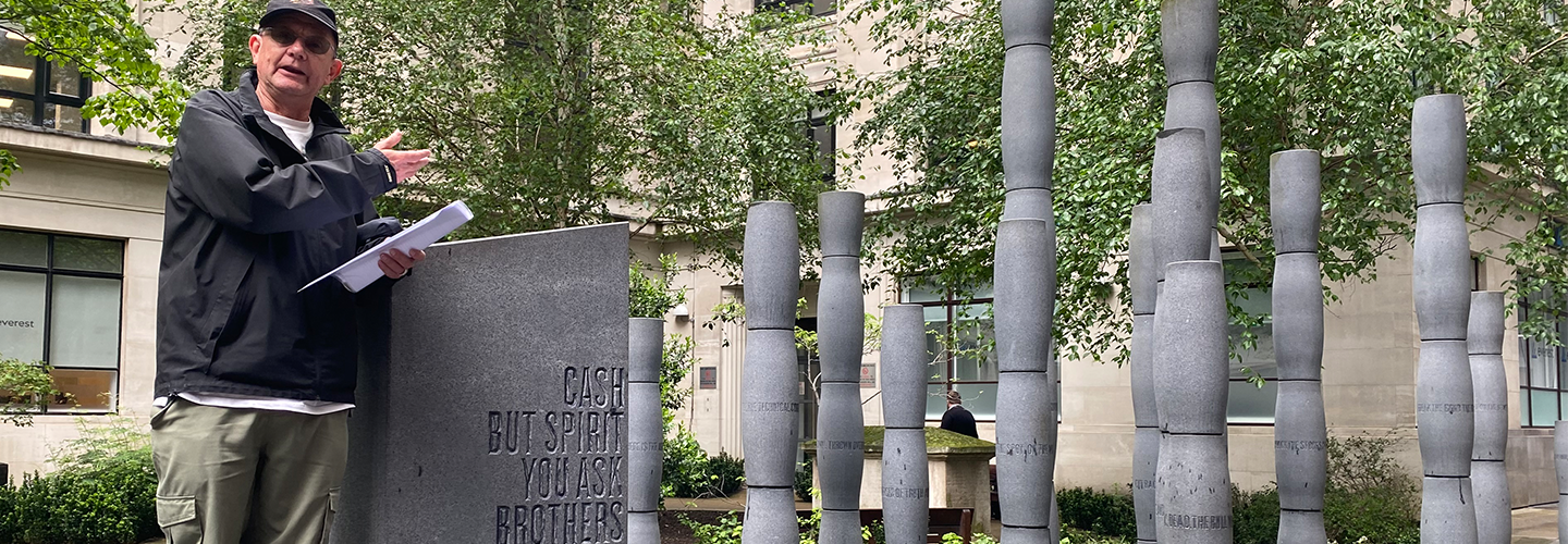 A man stands near a memorial sculpture