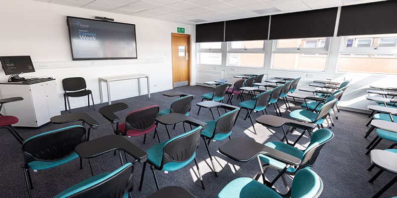 Empty teaching room set up with chairs towards digital screen