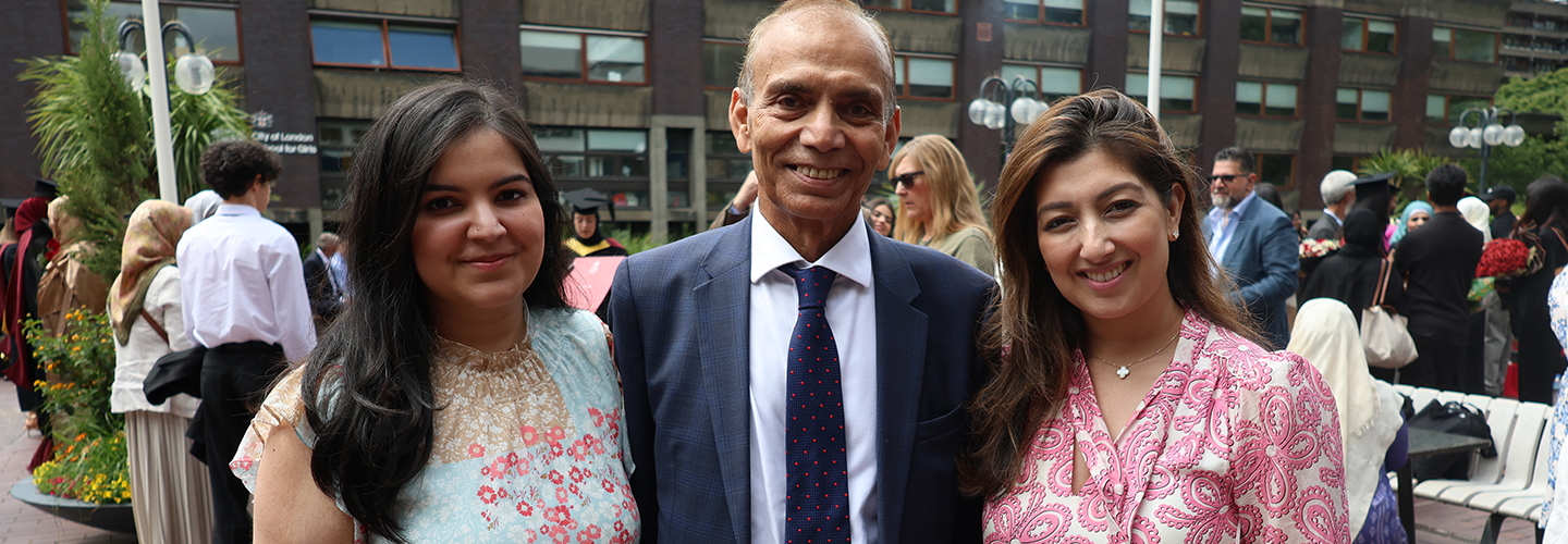 A man smiles with his two adult daughters