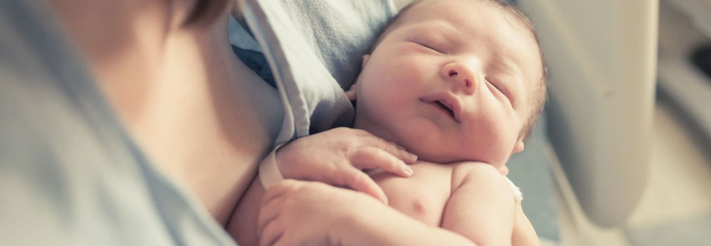 New born baby boy resting in mothers arms.