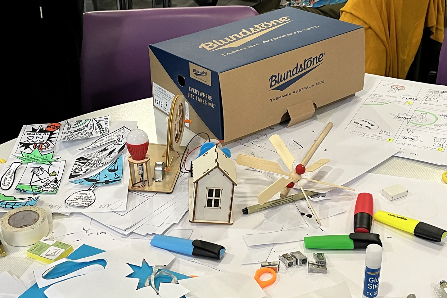 Comics, small wooden sculptures and craft materials scattered across a table.