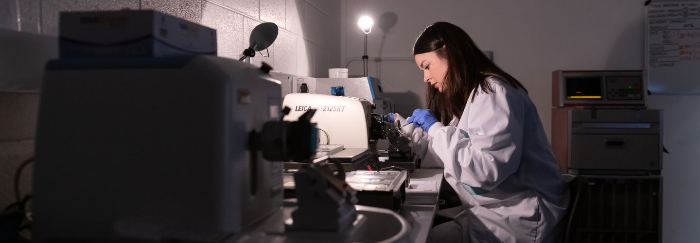 Women in dark lab looking into microscope