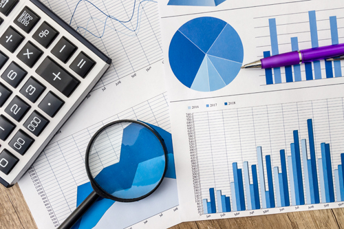 a pile of graphs, with a magnifying glass and calculator