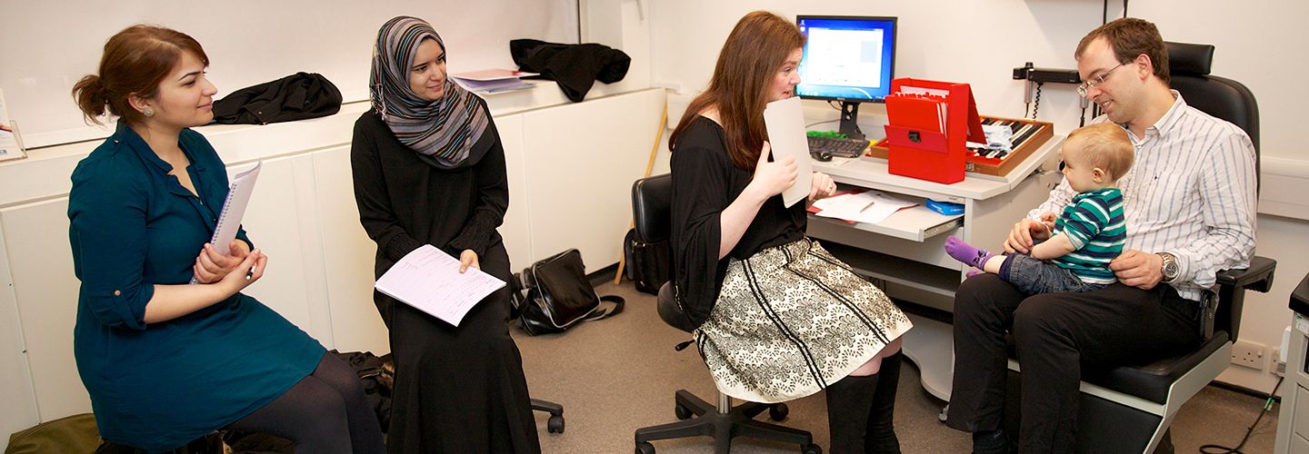 Postgraduate students in practical lesson with baby and father seated
