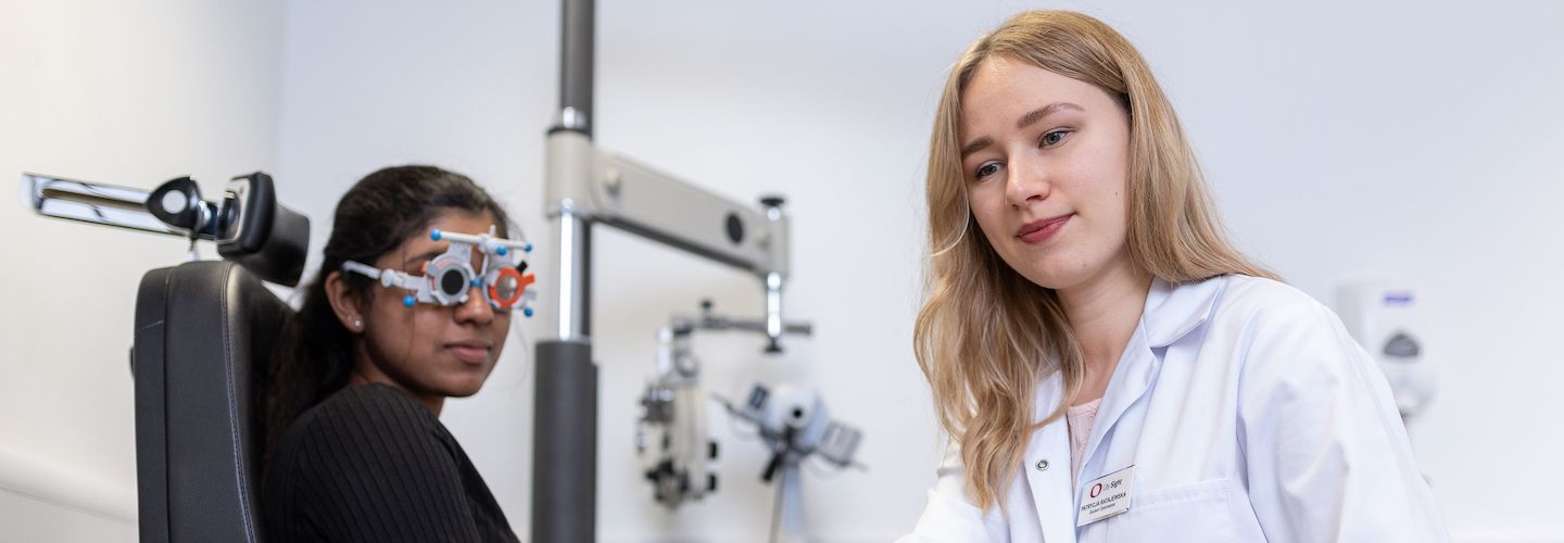 Student taking eye test of female patient
