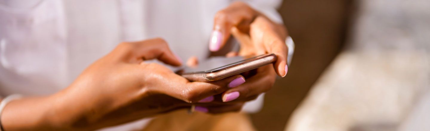 A close-up of a woman's hands as she uses her smartphone