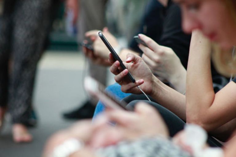 A group of teens all looking at their mobile phones