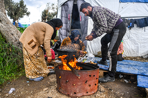 Man and woman light a fire in Moria refugee camp