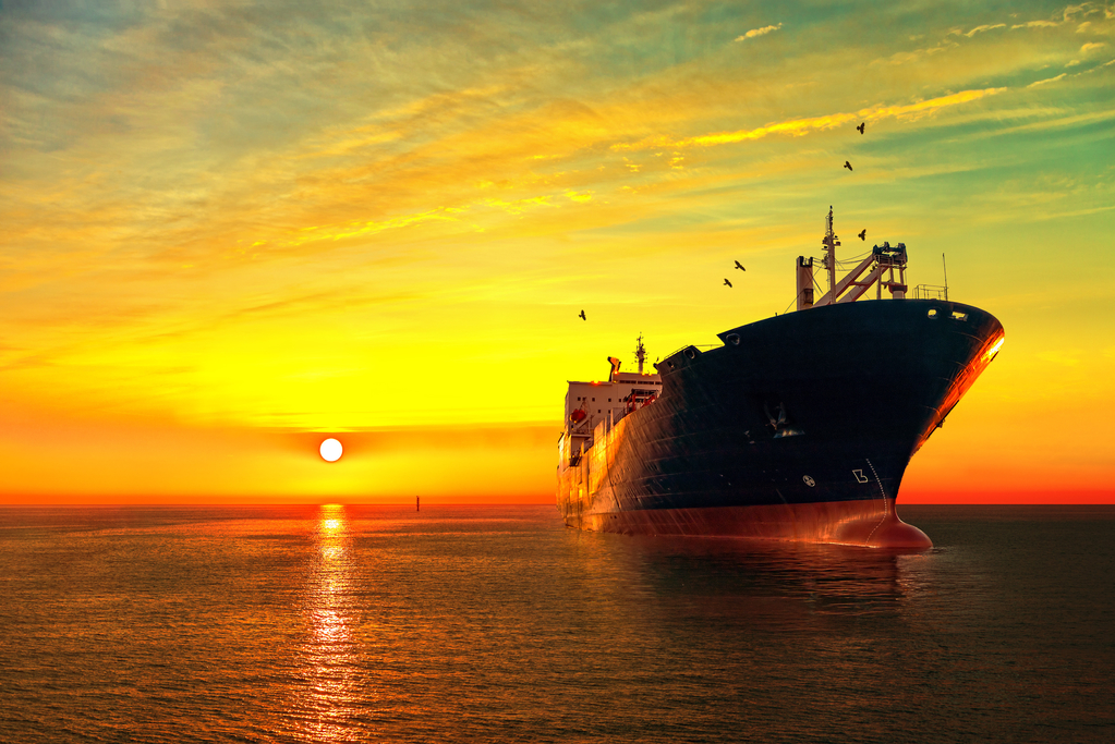 A large ship in the ocean as the sun sets
