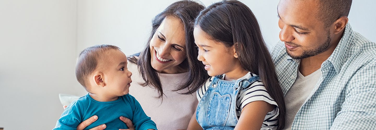 Multi-ethnic family playing with happy baby son at home