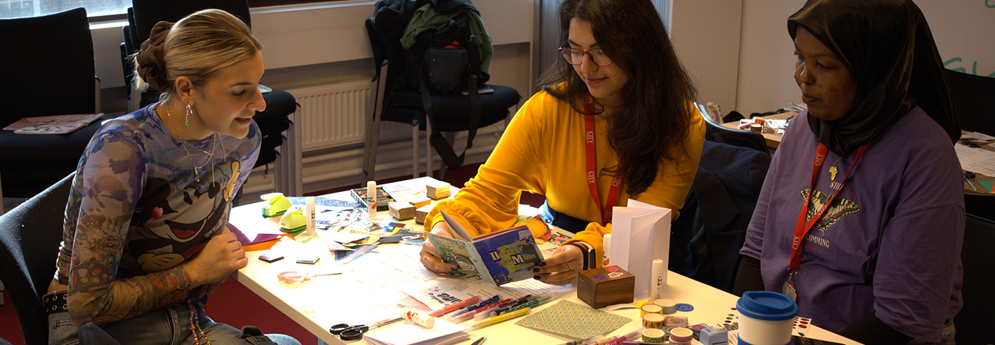 A group of people sit at a table with crafts materials 