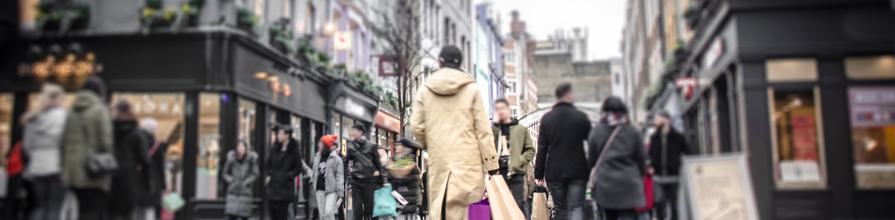 Abstract motion blurred shopper carrying shopping bags on crowded London street