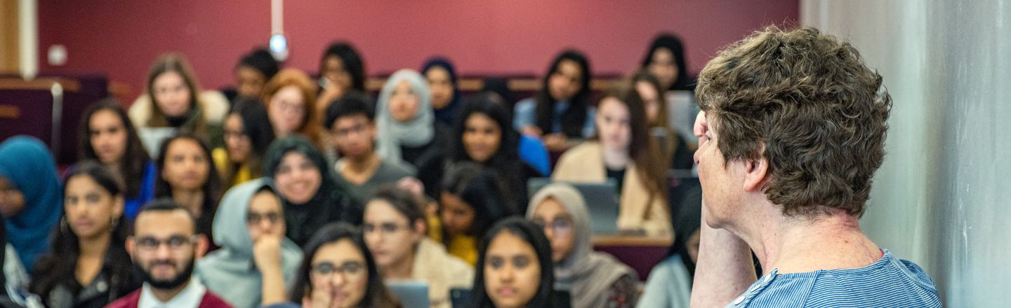 Lecturer giving a lecture to a crowded lecture theatre.