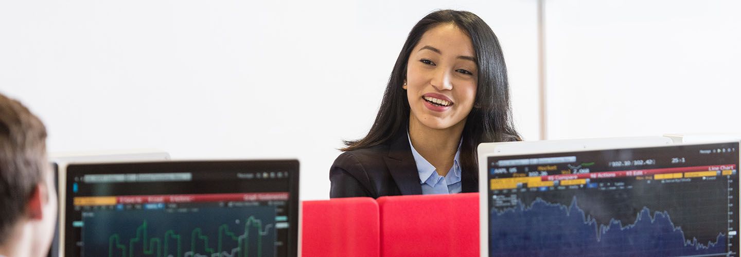 Female and male student have a conversation over the Bloomberg Terminals.