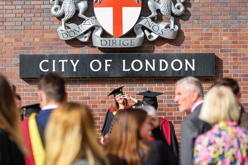 One graduate poses in front of the City of London sign. 