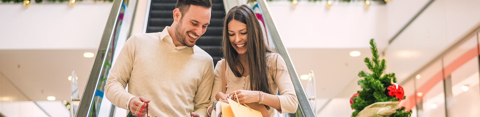 Man and woman walking down an escalator with shopping bags at Christmas