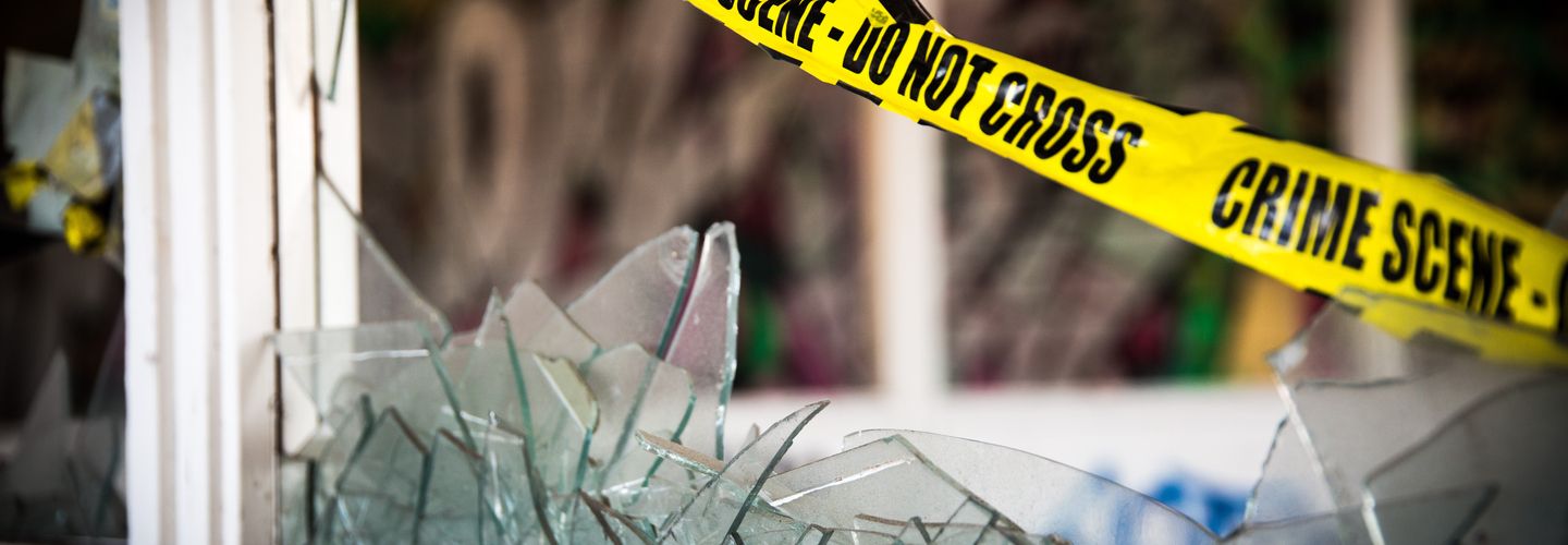 Yellow police tape over broken window