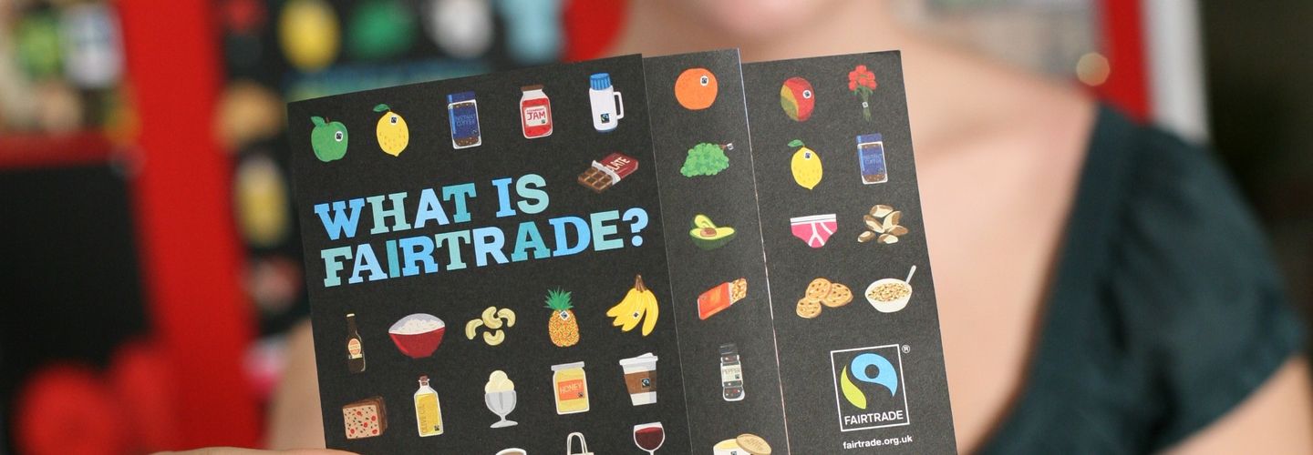 Woman holds up Fairtrade flyer showing a variety of food products with Fairtrade stickers on them